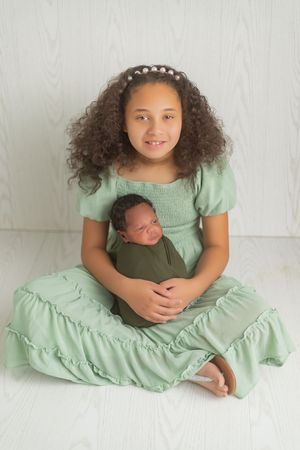 A series of four connected photos showing a young person in a mint green dress sitting against a white backdrop.