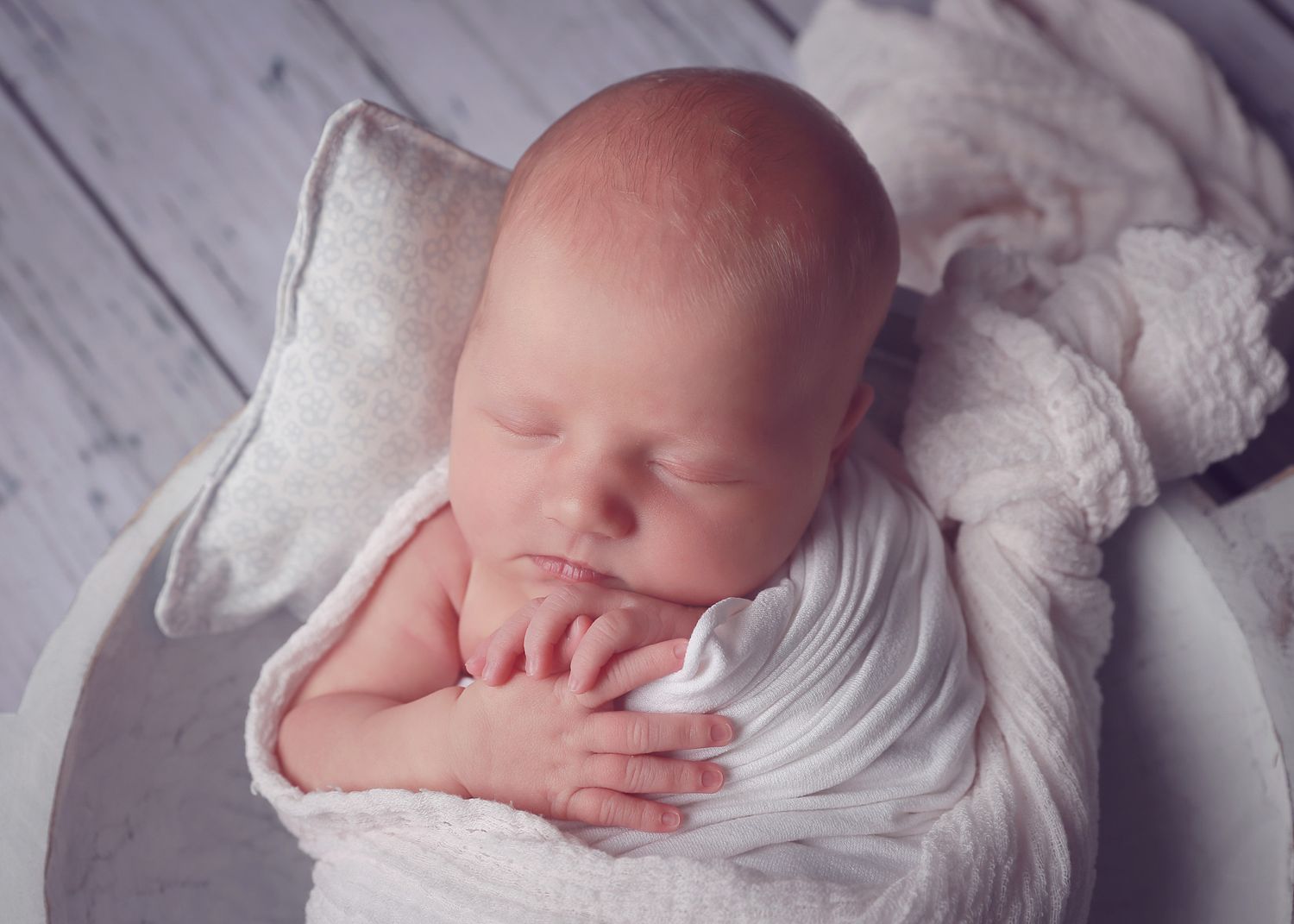 A peaceful newborn baby girl wrapped in soft fabrics, captured in a serene and intimate setting, showcasing the delicate beauty in photo
