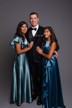 A photoshoot progression showing a family trio in formal attire against a dark backdrop with teal and navy dresses.