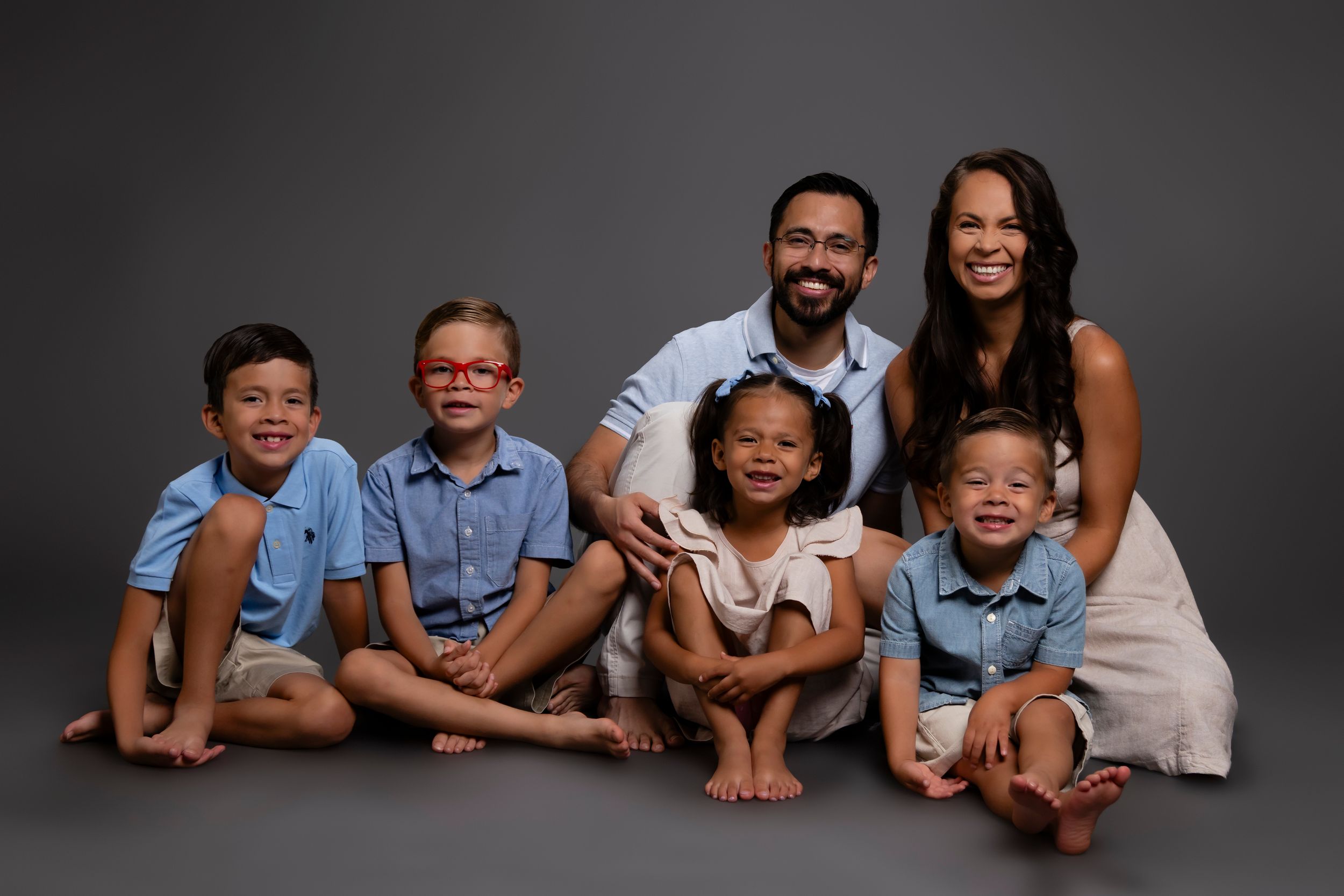A family wearing coordinated blue and white outfits poses together across a series of black and white photos.