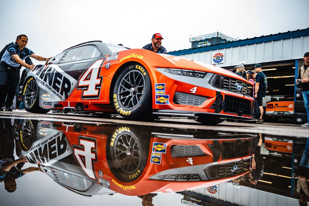 Race car reflection in polished floor showing mirror image of vehicle and track.