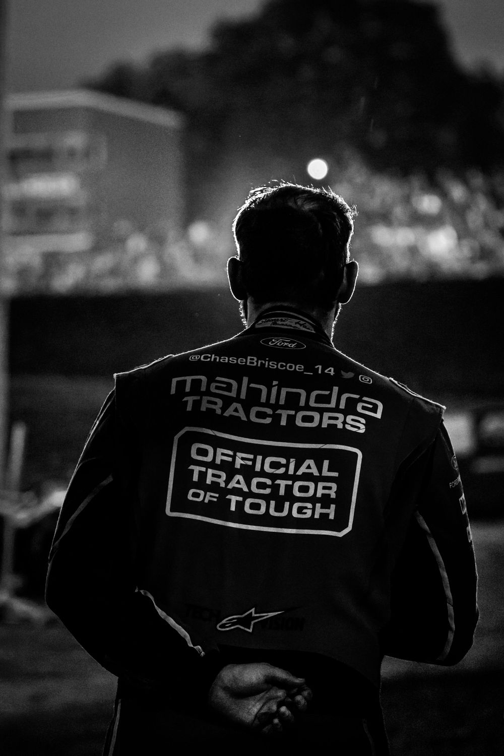 Silhouettes of racing team members wearing Mahindra branded uniforms at dusk.