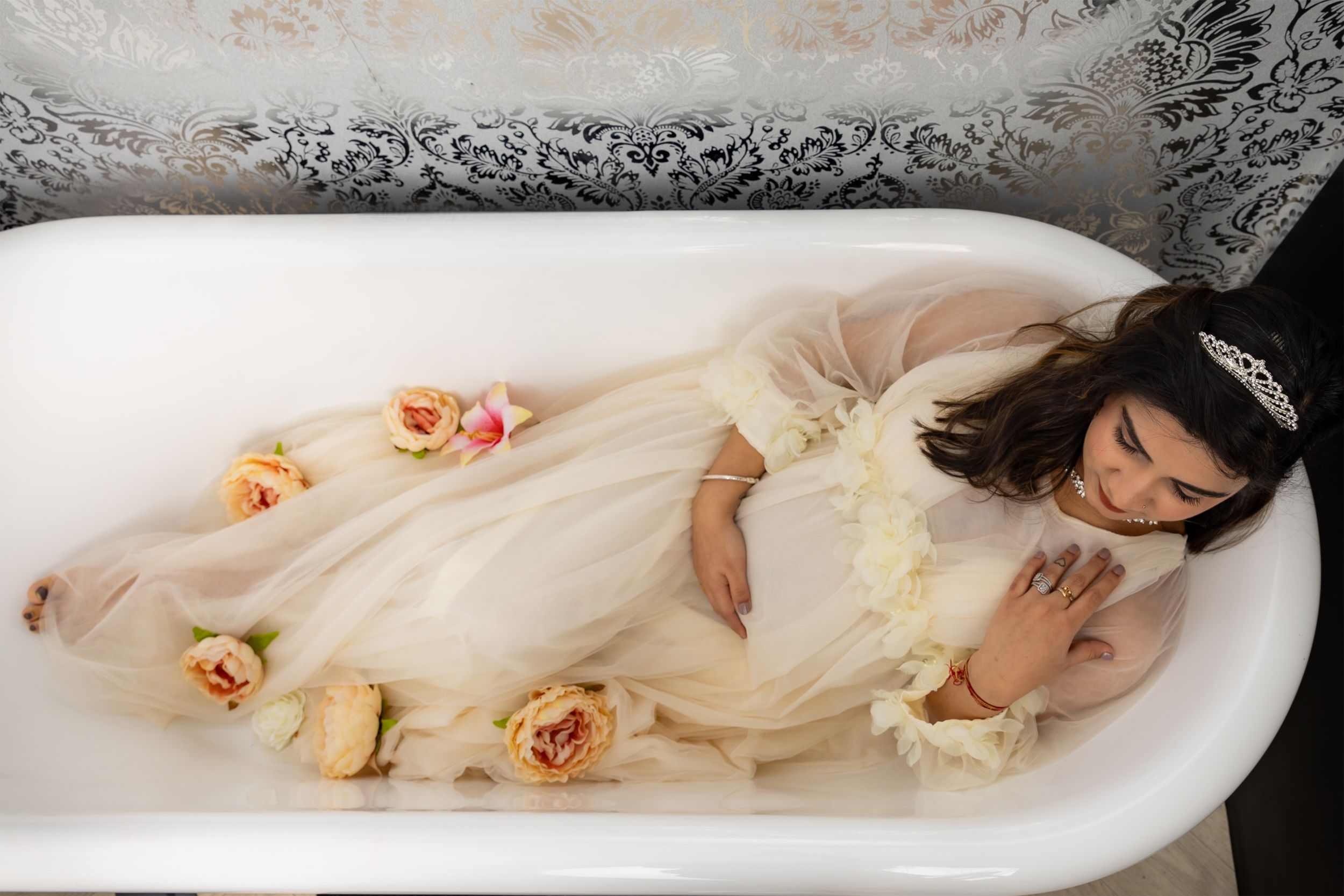 A romantic bathtub scene decorated with peach roses and filled with delicate tulle fabric in soft lighting.