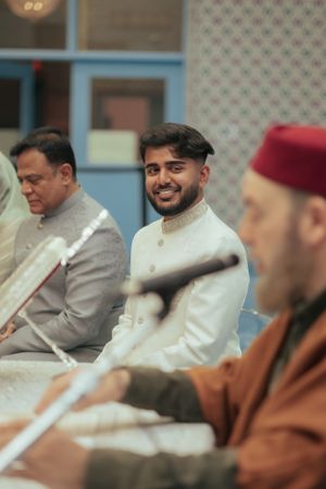 Men in traditional formal attire seated during cultural ceremony.