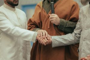 Two people shake hands while wearing traditional formal attire.