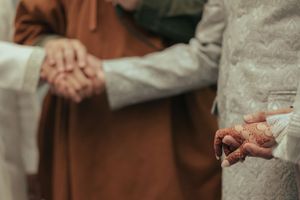 Close-up of hands during traditional wedding ceremony handshake ritual.