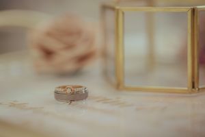 Wedding ring with textured band photographed next to gold geometric display box.