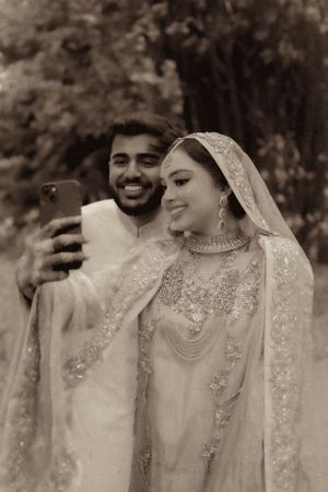 A couple takes a selfie together in traditional wedding attire.