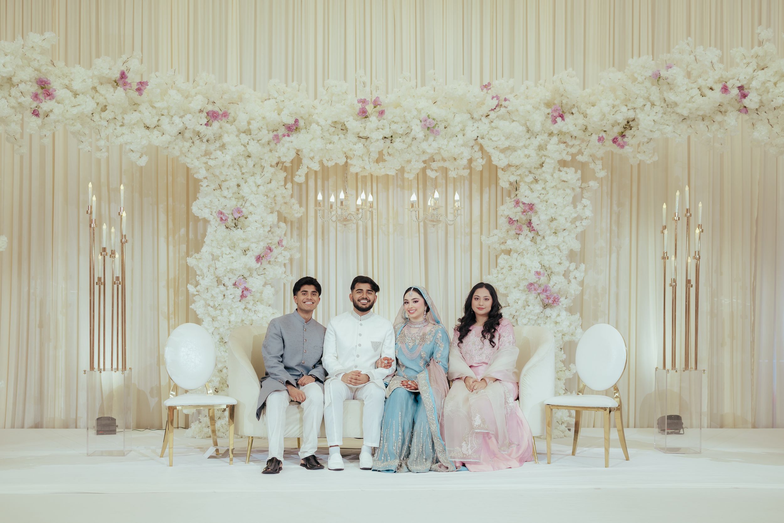 Wedding stage setup with floral backdrop and formal seating arrangement for special ceremony.