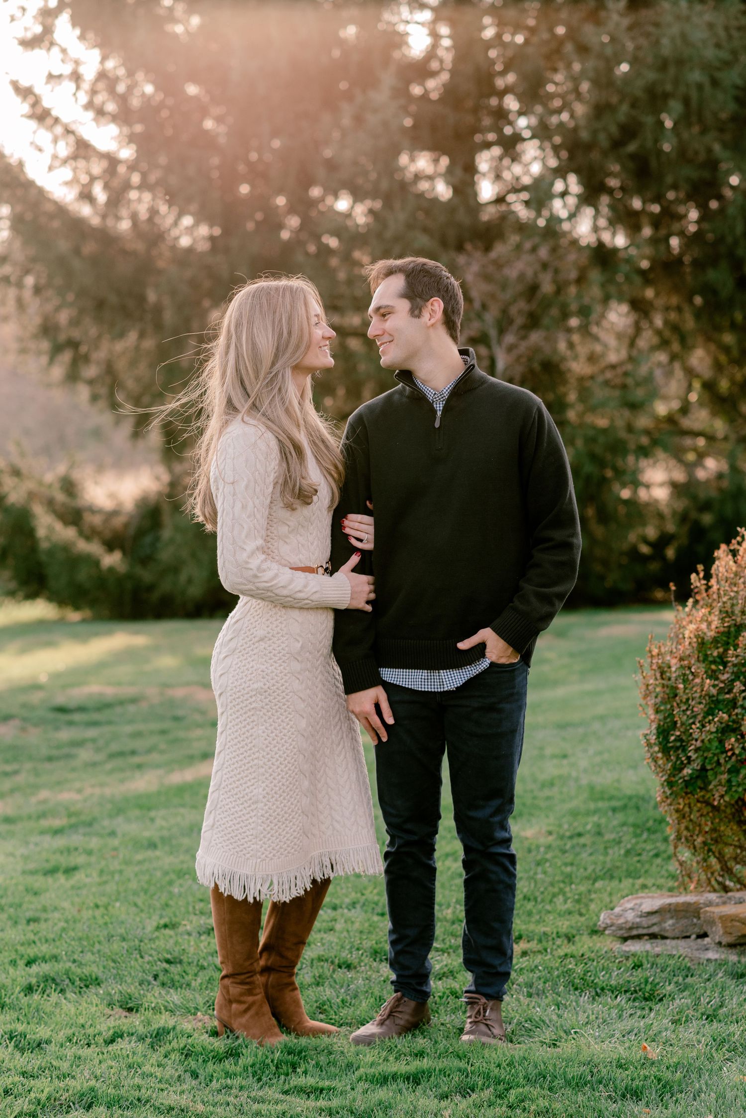 Couple embracing in autumn forest with golden sunlight streaming through trees.