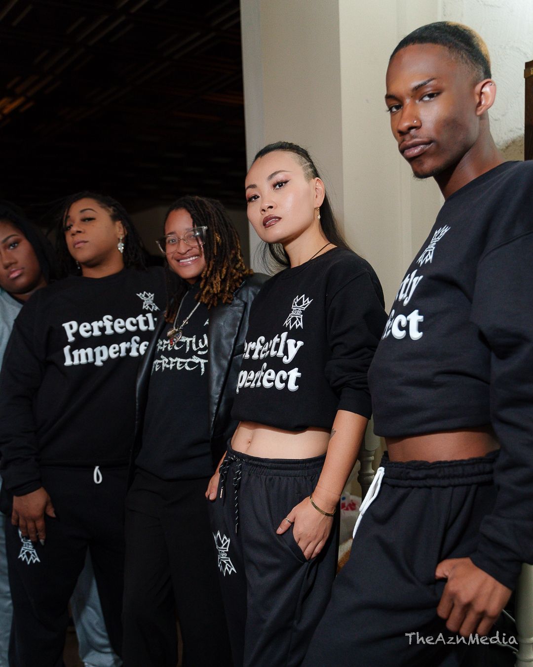 Group wearing matching black 'Perfectly Imperfect' sweatshirts posing together.
