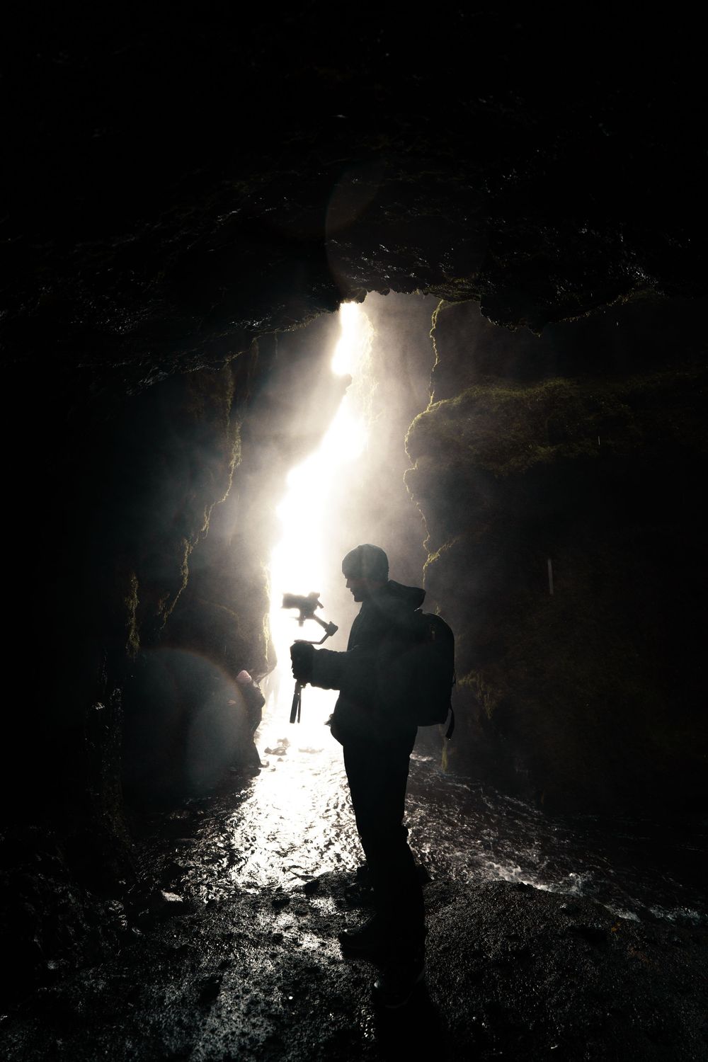 Silhouette of an explorer in a dark cave with dramatic light streaming through.