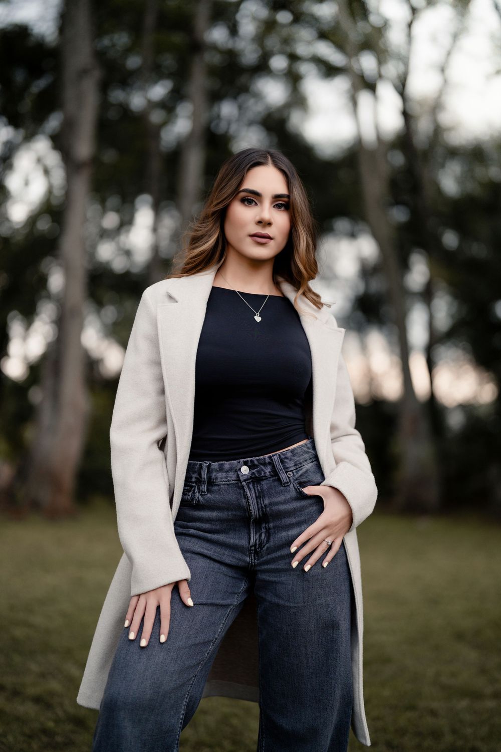 Fashion portrait showcasing a cream coat and dark denim in an outdoor setting.