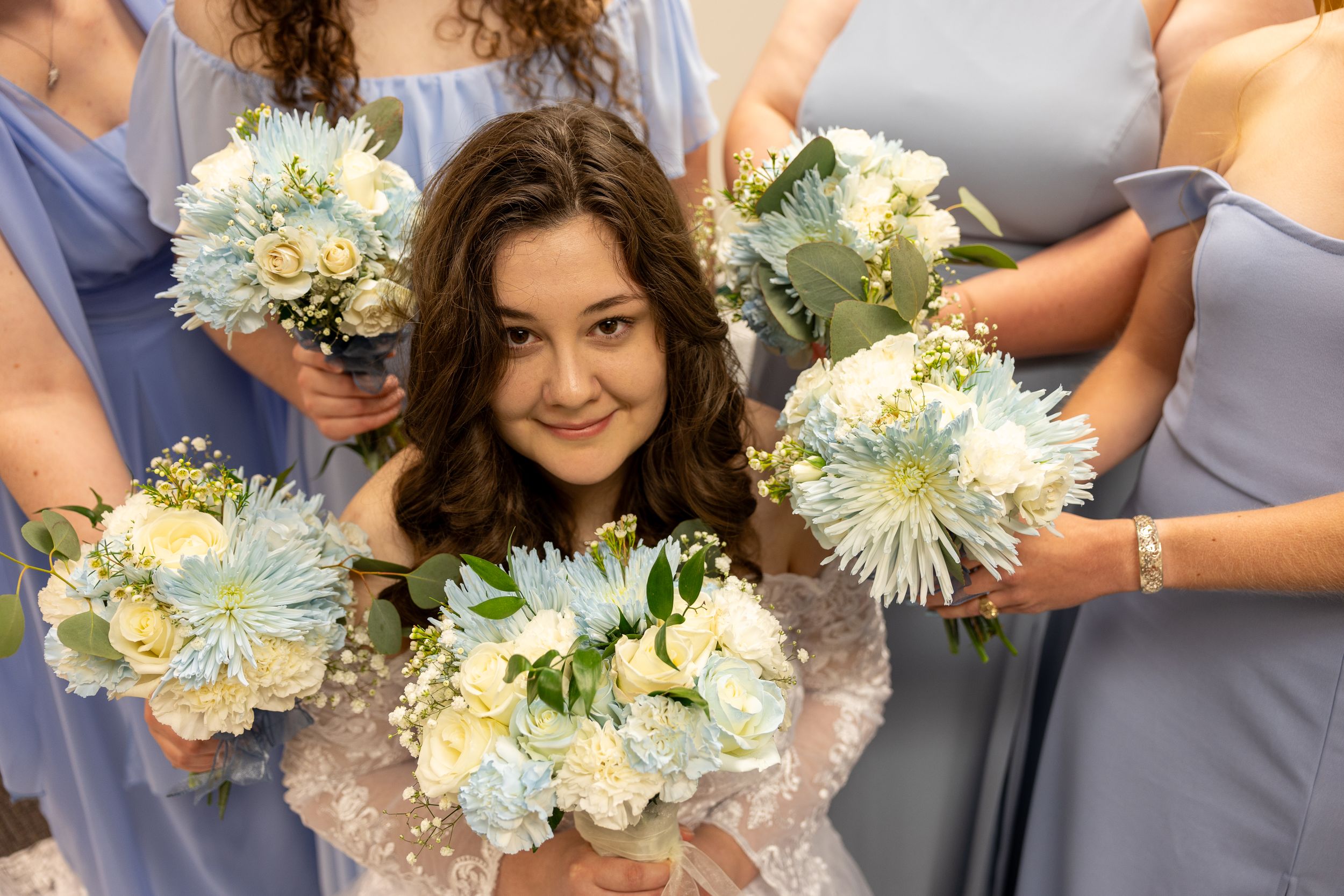 Bridesmaids in lavender dresses hold coordinated white and cream floral bouquets.