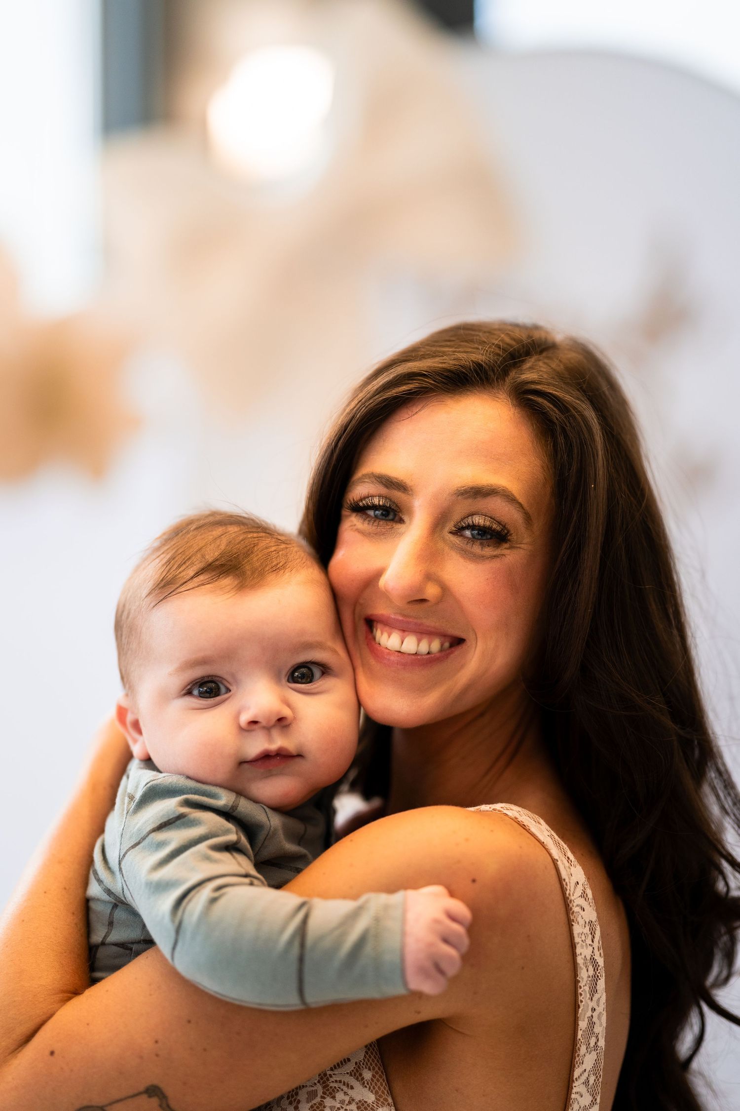 A tender moment between a woman in lace and an infant in blue.