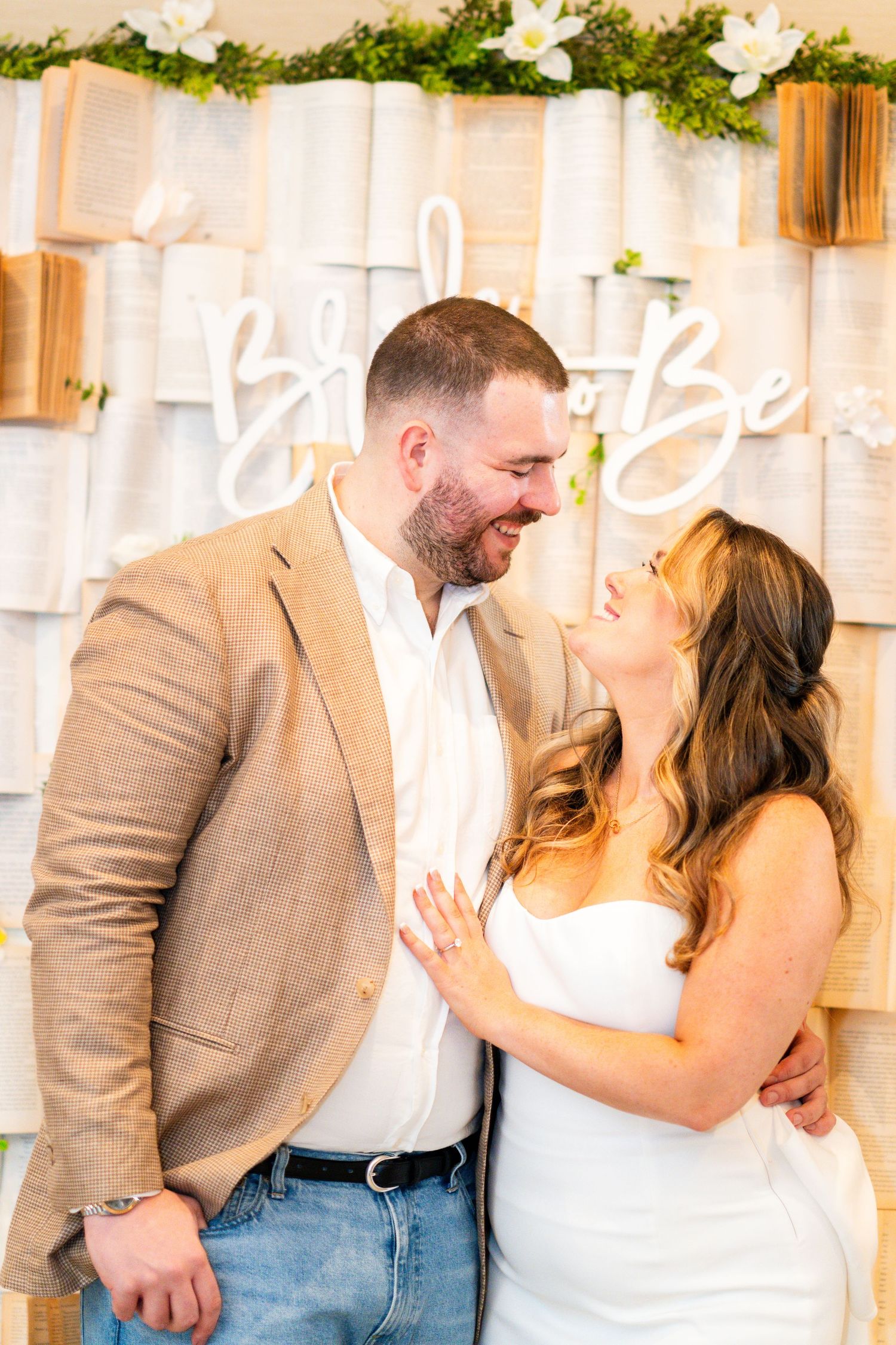 A couple sharing a loving moment in front of a decorative book page backdrop.