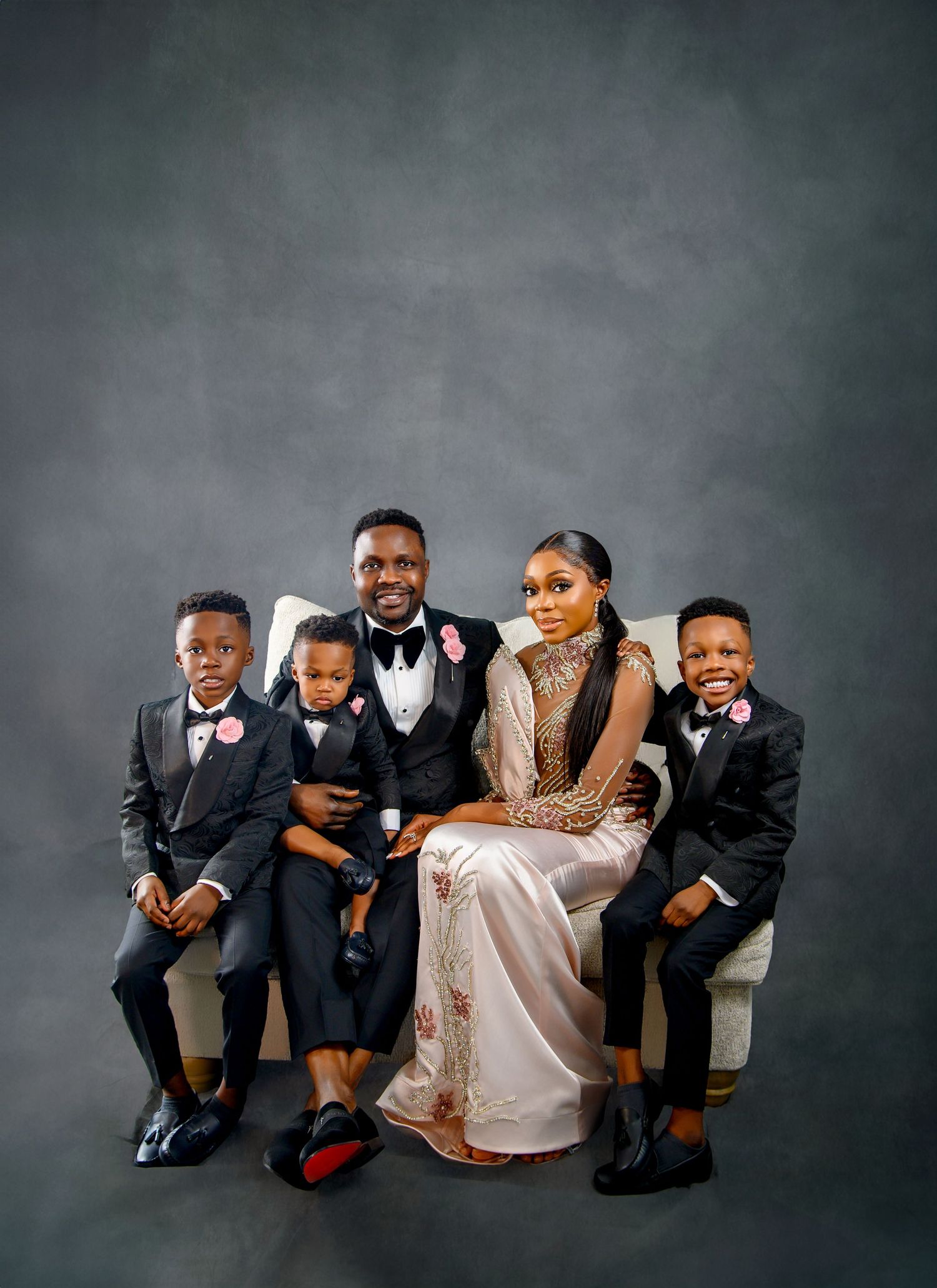 Studio family portrait against grey background with formal attire.