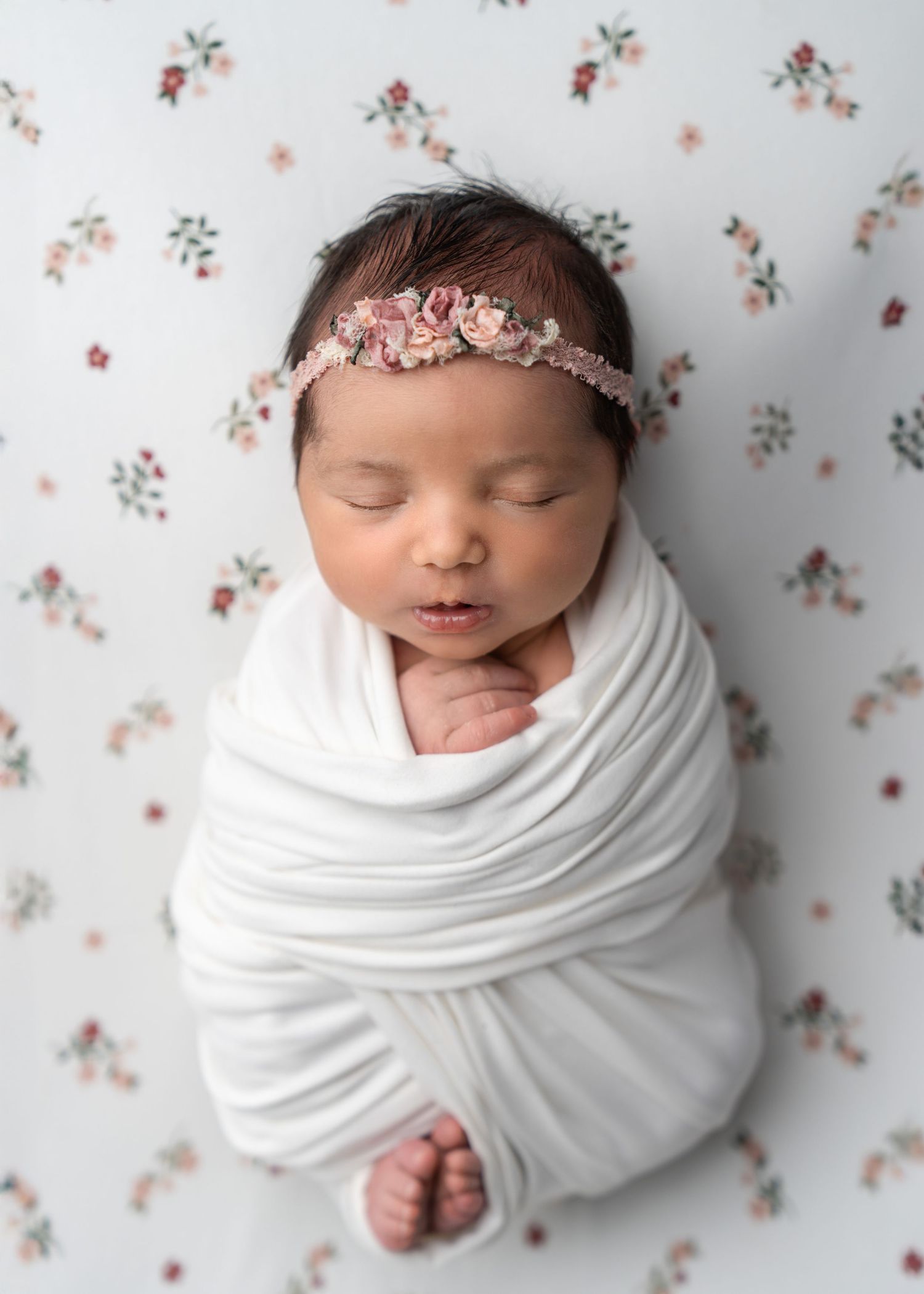 Peaceful sleeping newborn baby on soft white bedding in natural light.