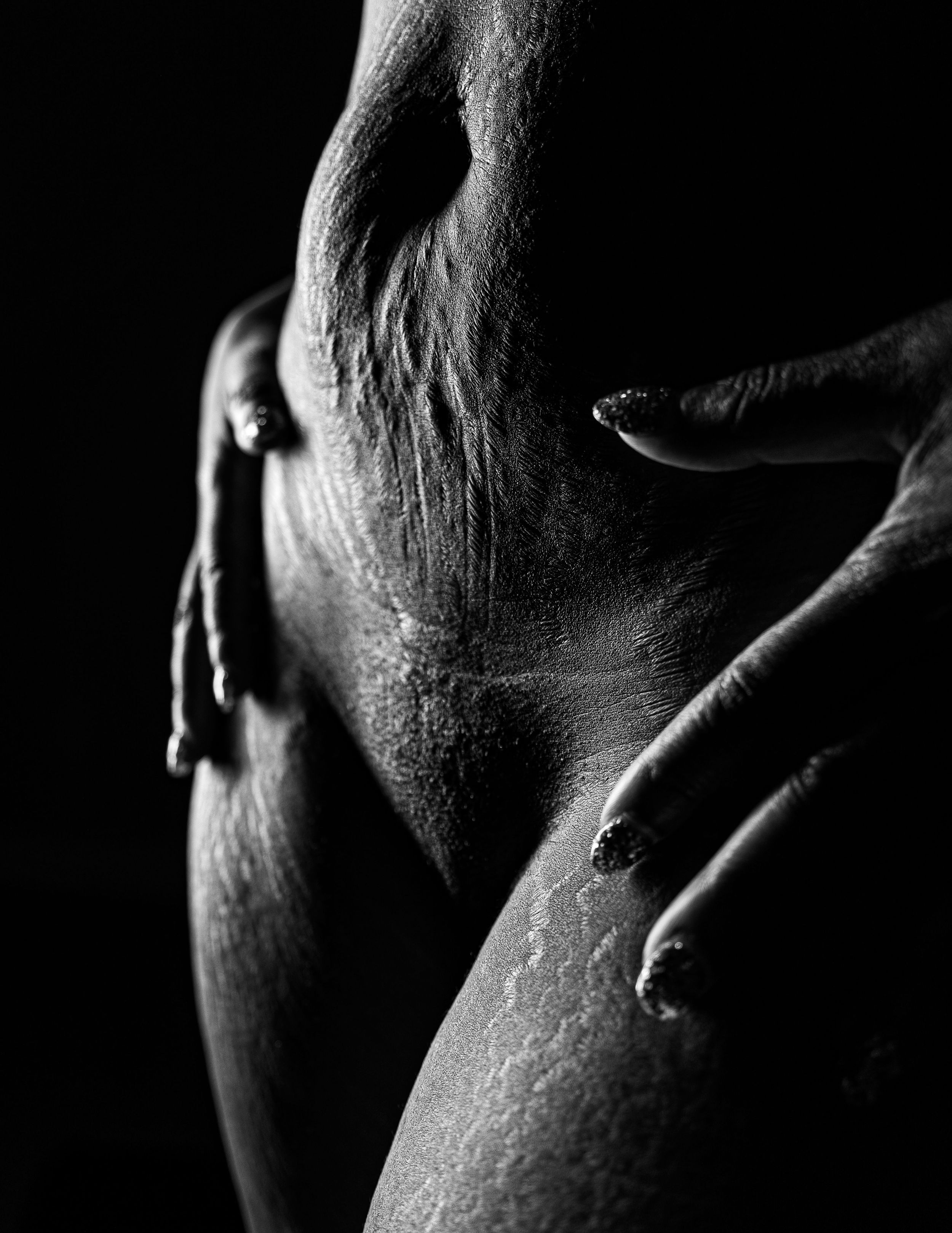 Artistic black and white photograph showing a close-up silhouette of a neck and fingers in dramatic lighting.