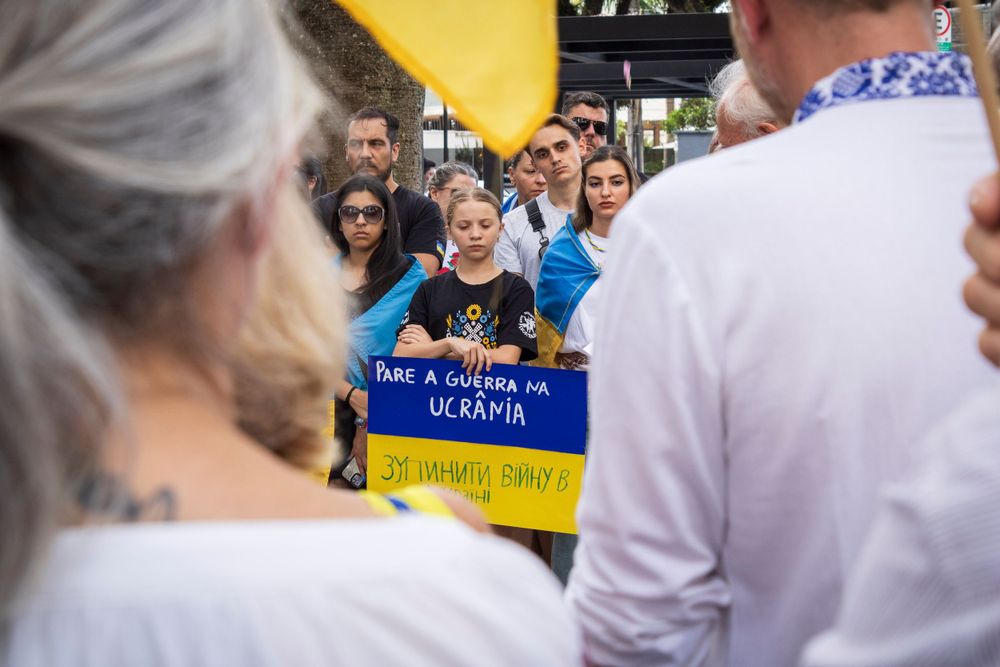 Crowd at solidarity gathering holding Ukrainian flag in Curitiba, photographed by Piret Victoria Ribas.