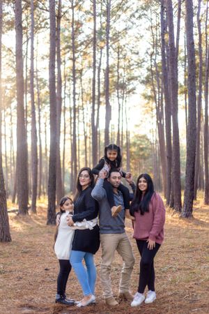 Group photo of a family enjoying time together in a sunlit pine forest.