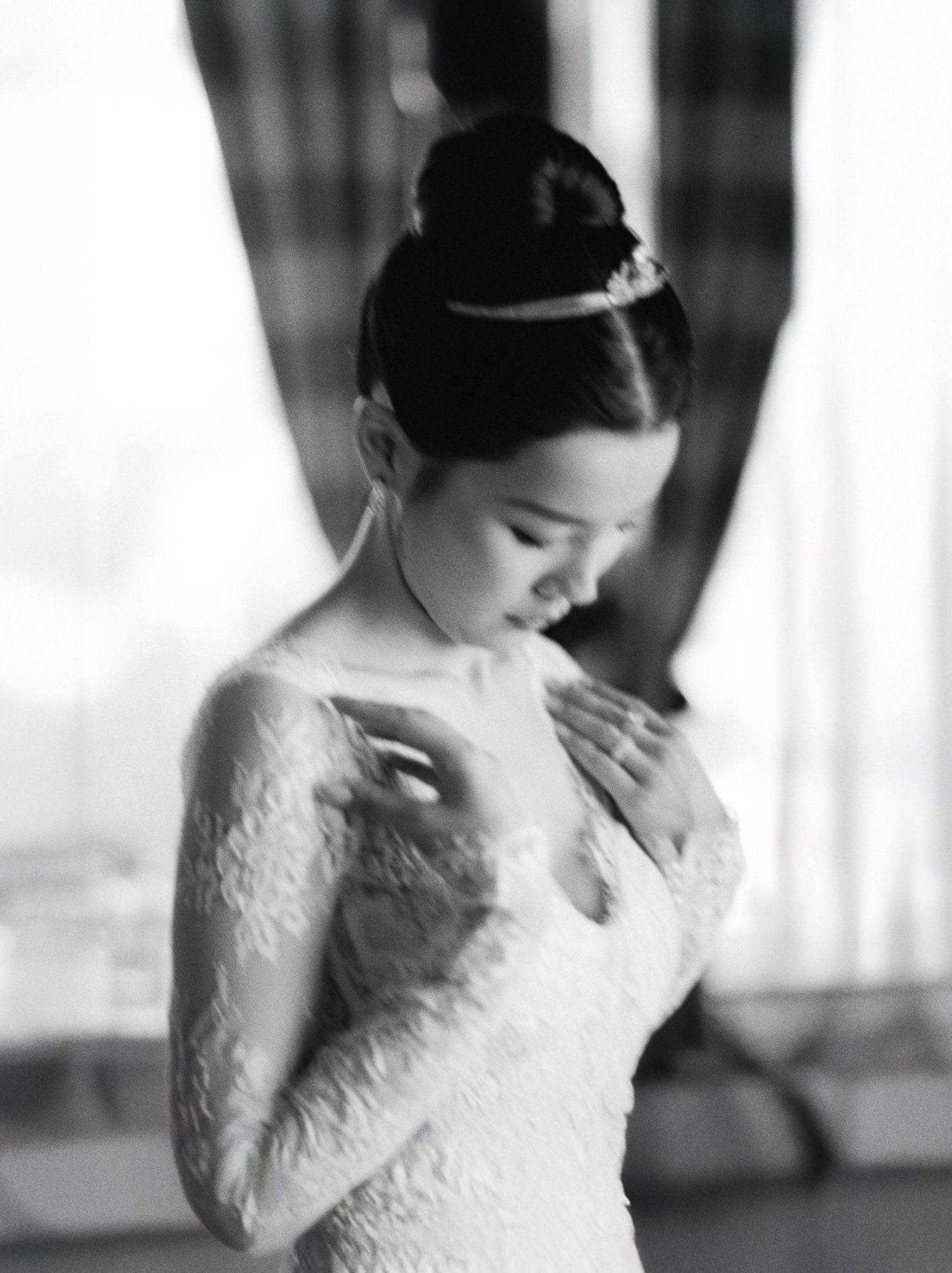 Black and white photo of a bride in lace gown with elegant updo and tiara, looking down gracefully.