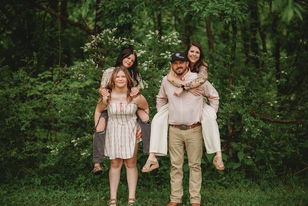 Group portrait in light colored clothing against natural greenery backdrop.