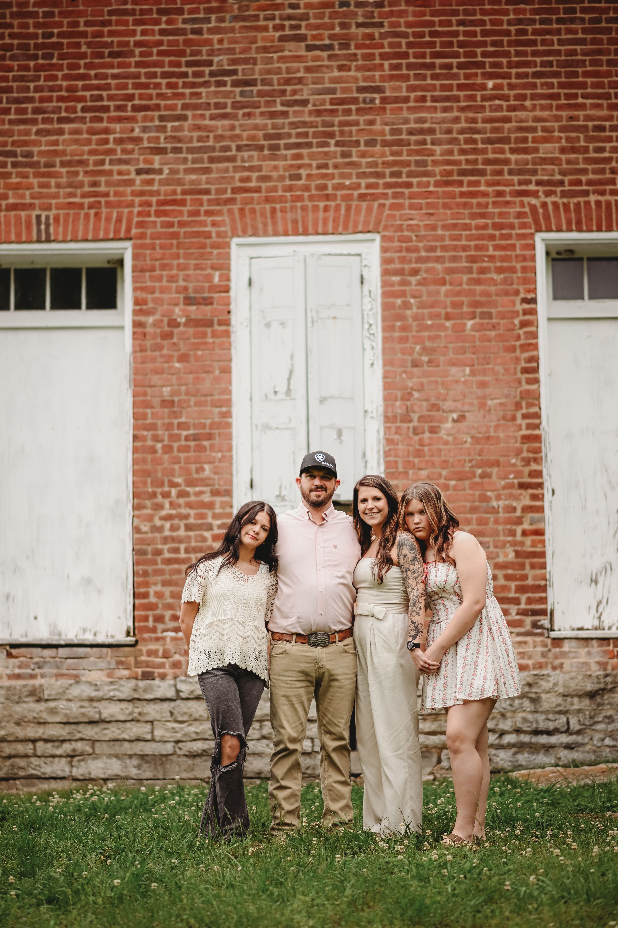 Group portrait against rustic red brick wall with white doors.