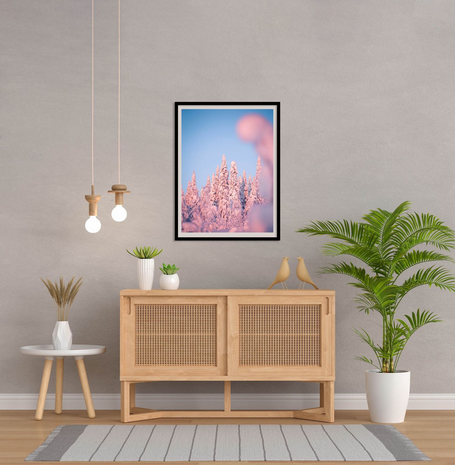 Framed pink winter landscape art print displayed above wooden sideboard in modern living room.