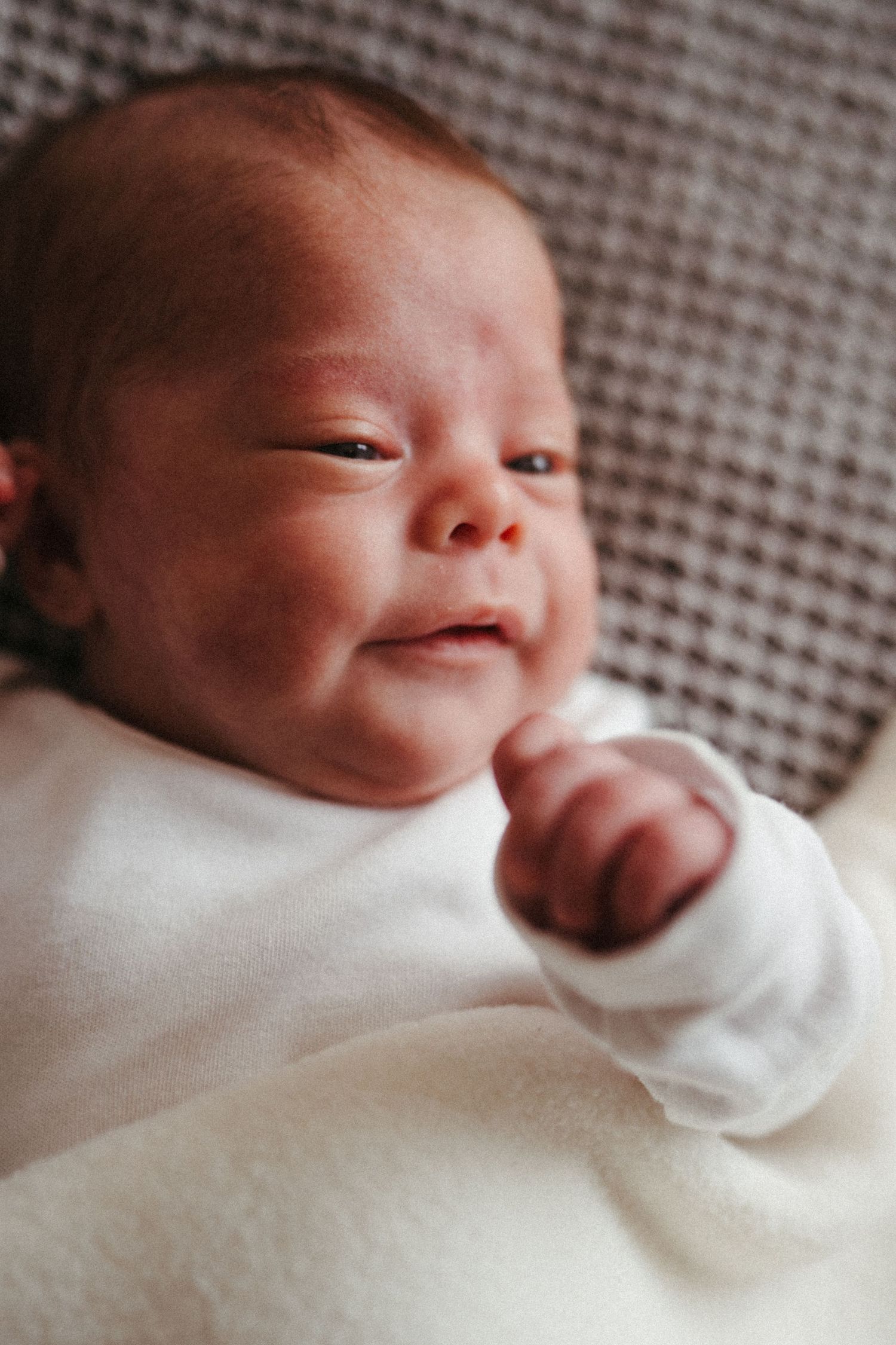 Close-up sequence of a newborn baby in white clothing showing various expressions.