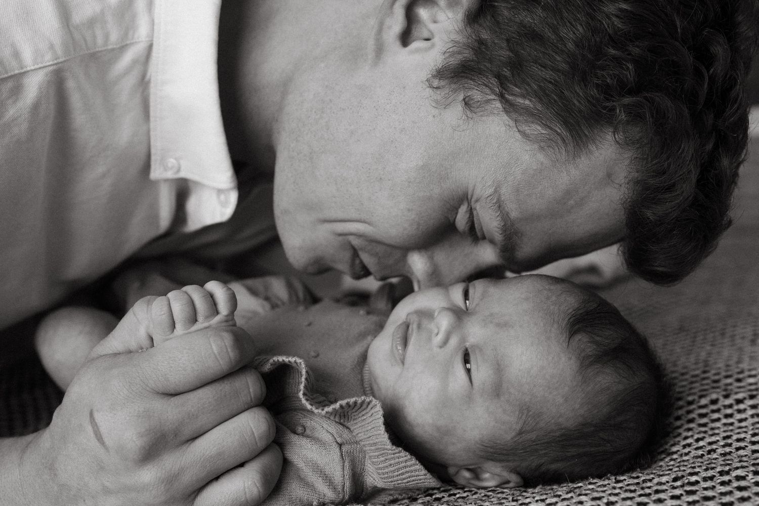 Intimate black and white portrait showing tender moments between a couple lying close together.