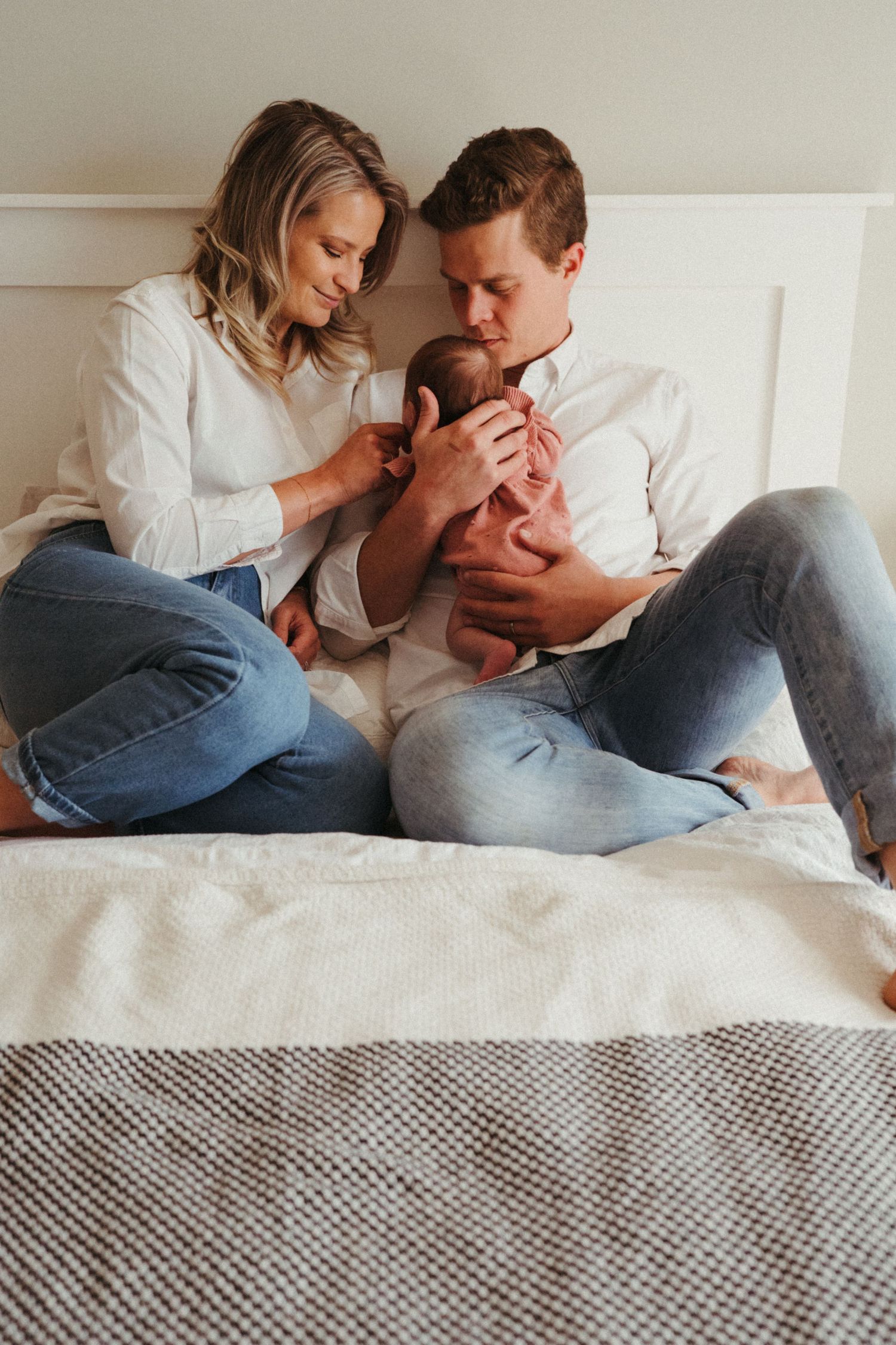 Couple in white shirts and jeans sharing intimate moments on white bedding.