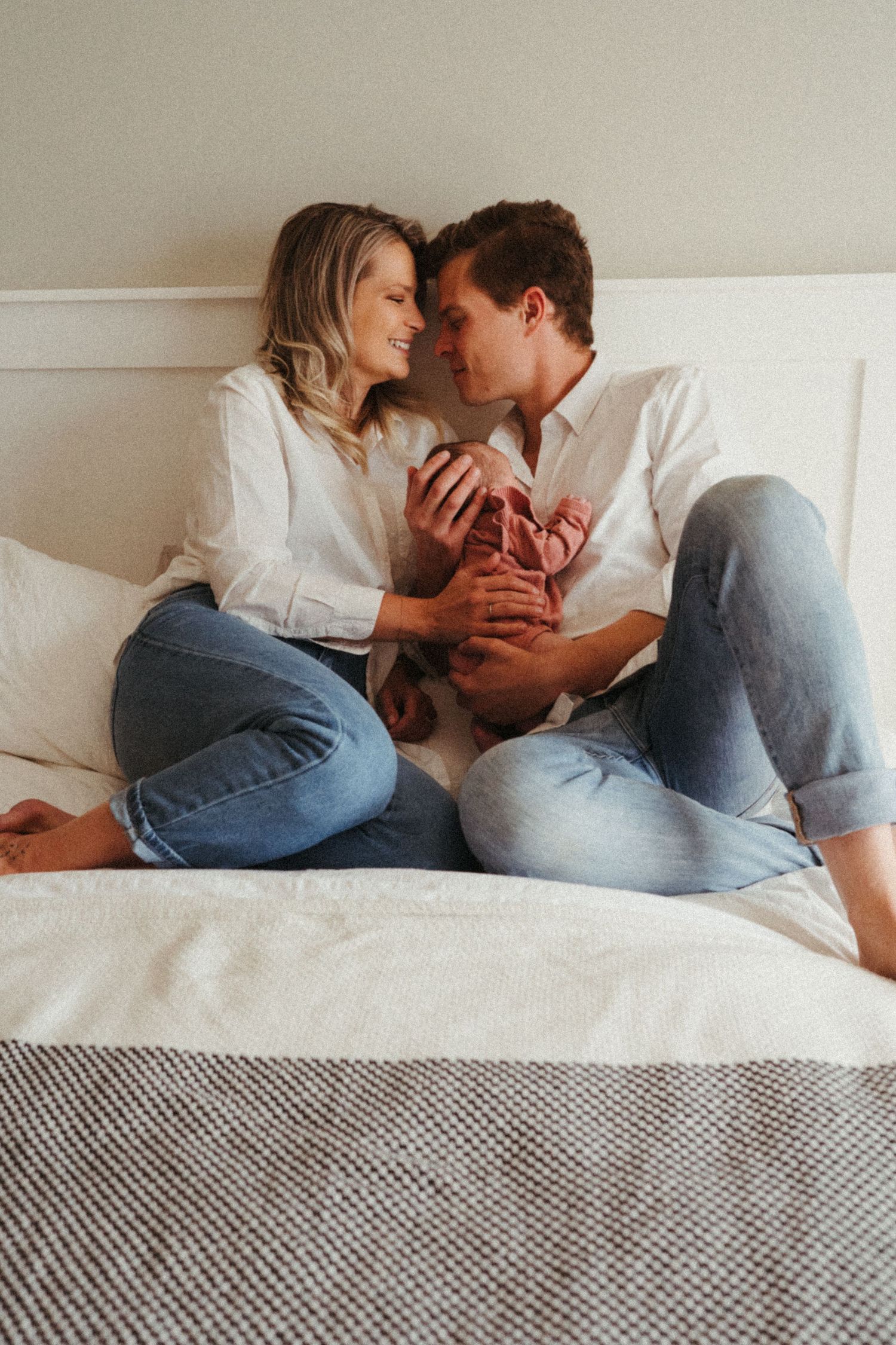 Lifestyle portrait showing tender moments between couple on white bed.