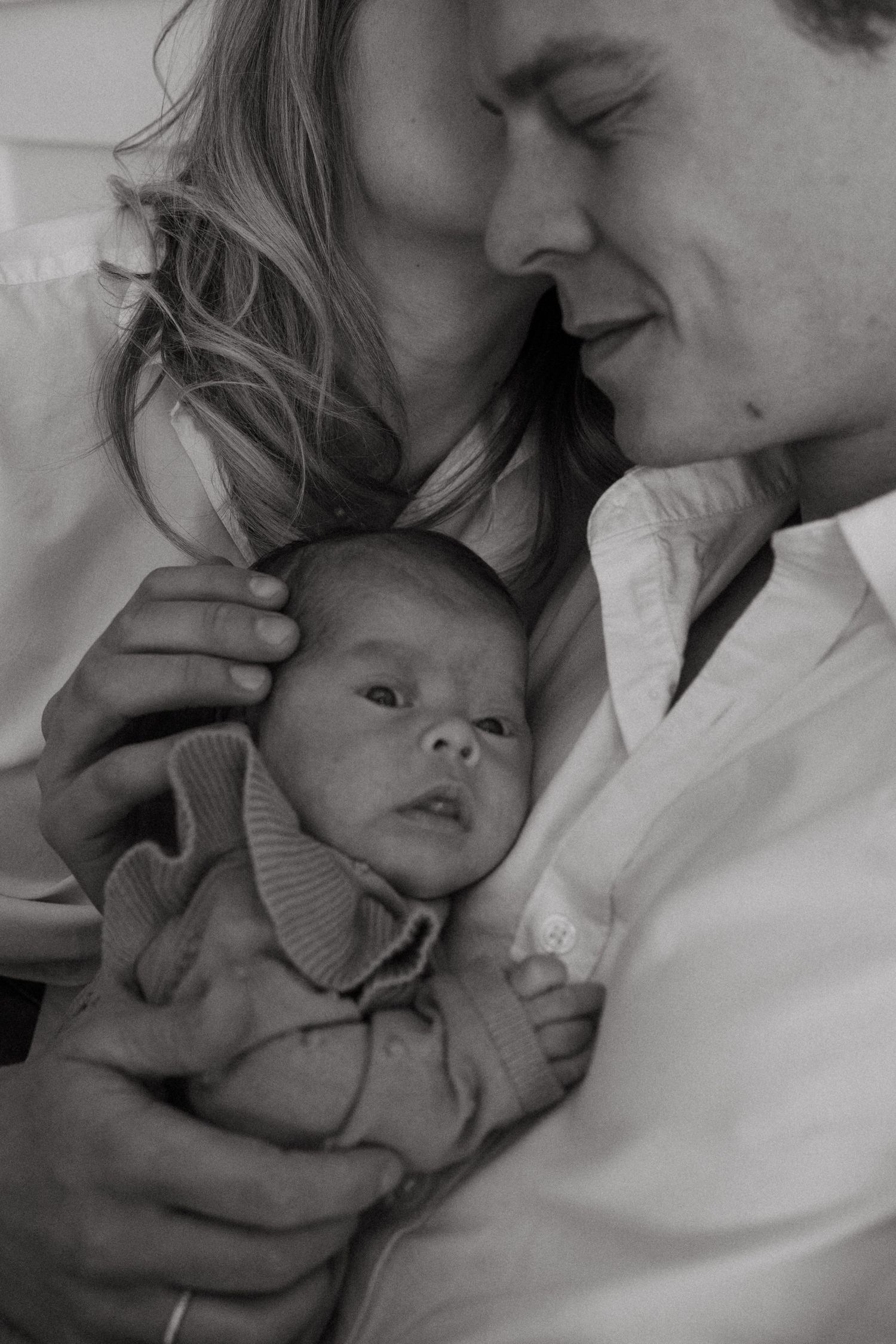 Black and white portrait of parents tenderly holding their newborn baby.