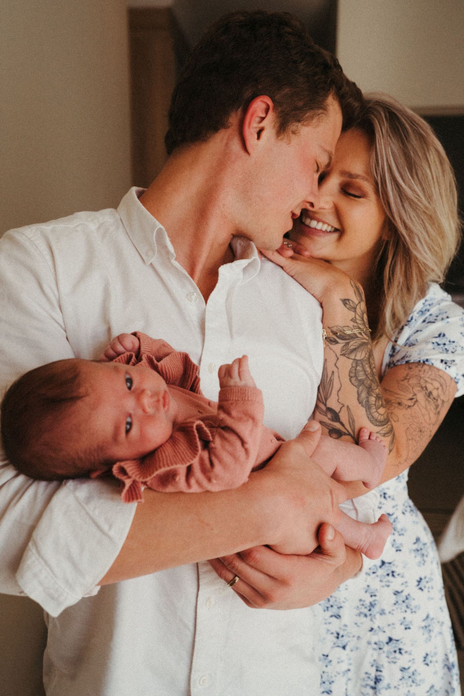 Joyful parents sharing an intimate moment while holding their crying newborn baby.