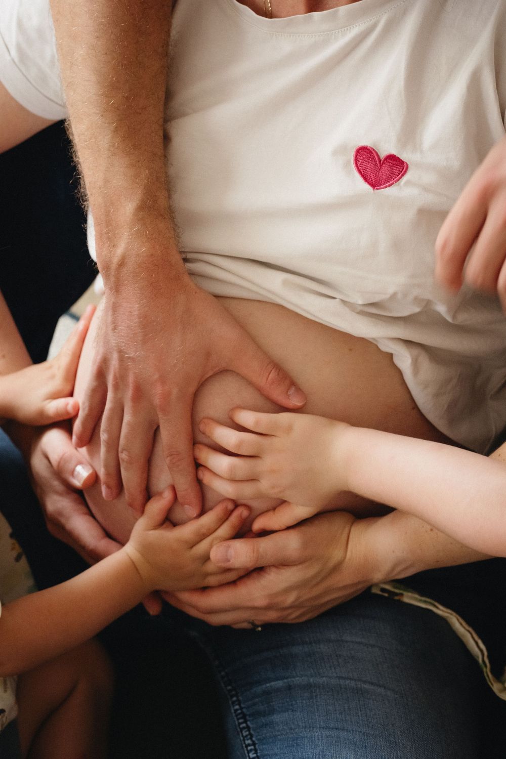 International family in Lyon putting hands in mom's belly.
