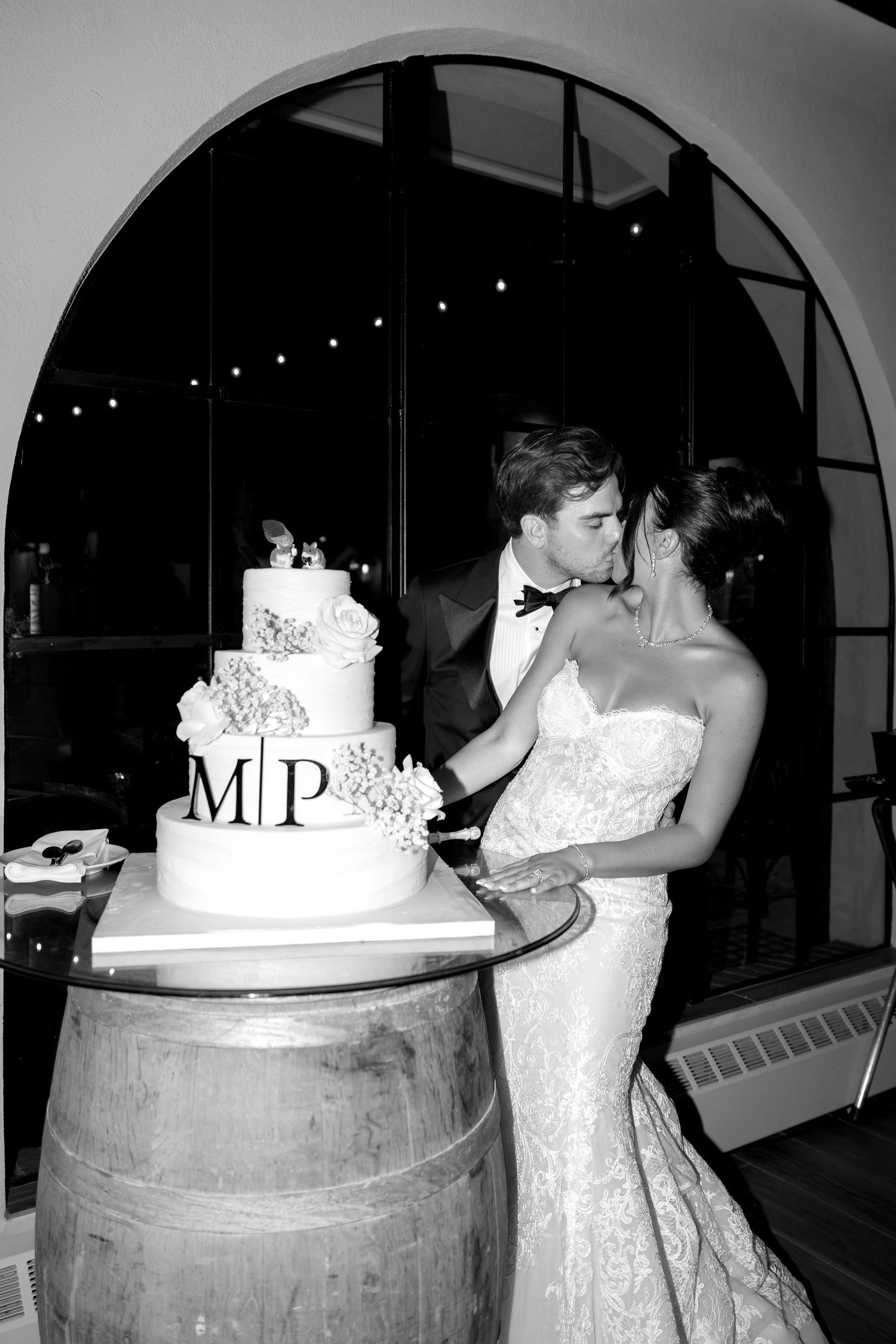 Wedding cake cutting moment on rustic wine barrel display.