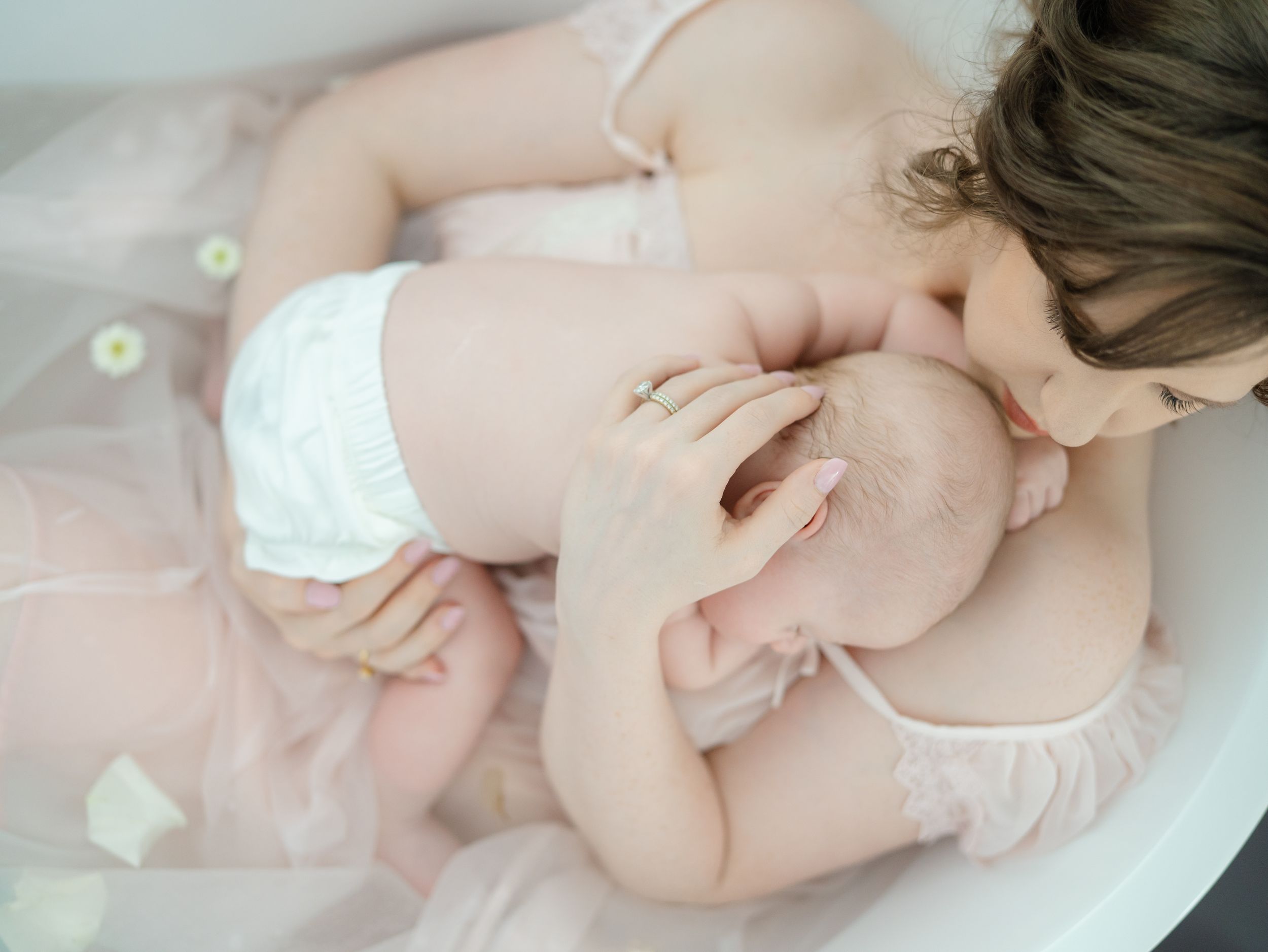 Mother and her newborn baby boy soak in a tub filled with florals while the moment is captured by Nj photographer.