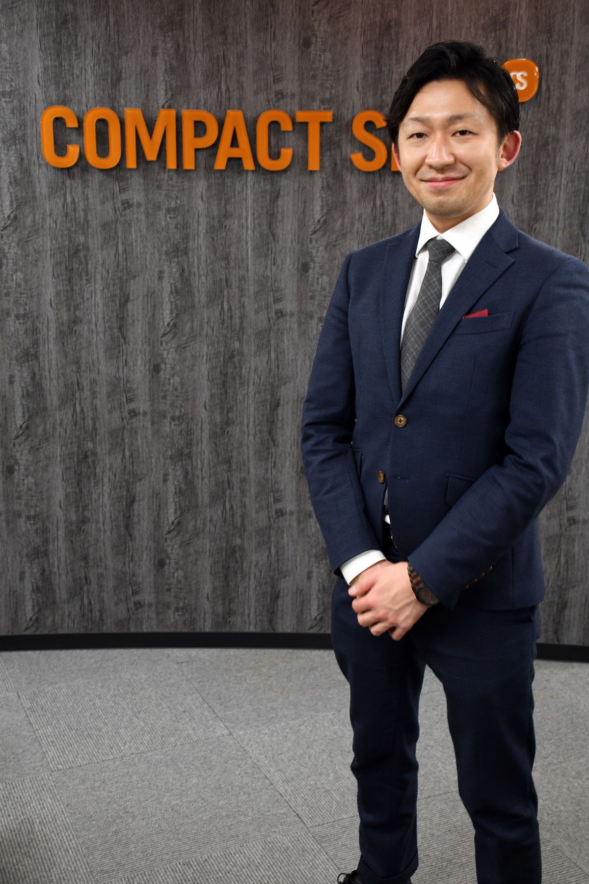 Professional Asian businessman in navy suit posing in front of Compact S office sign.
ハワイウェディングとハネムーンの専門旅行会社