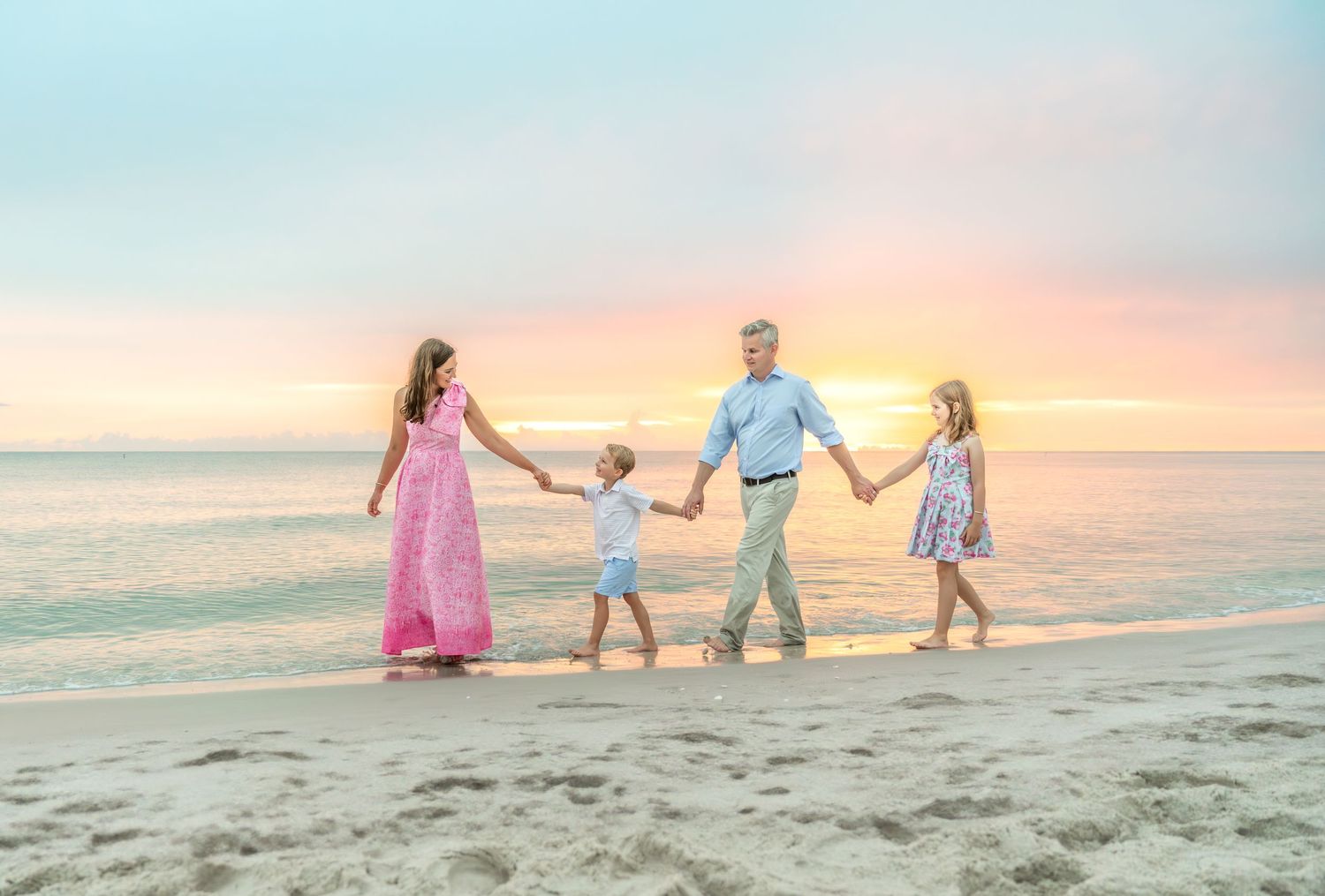 Tender embrace on beach with pastel sunset and ocean waves in background.