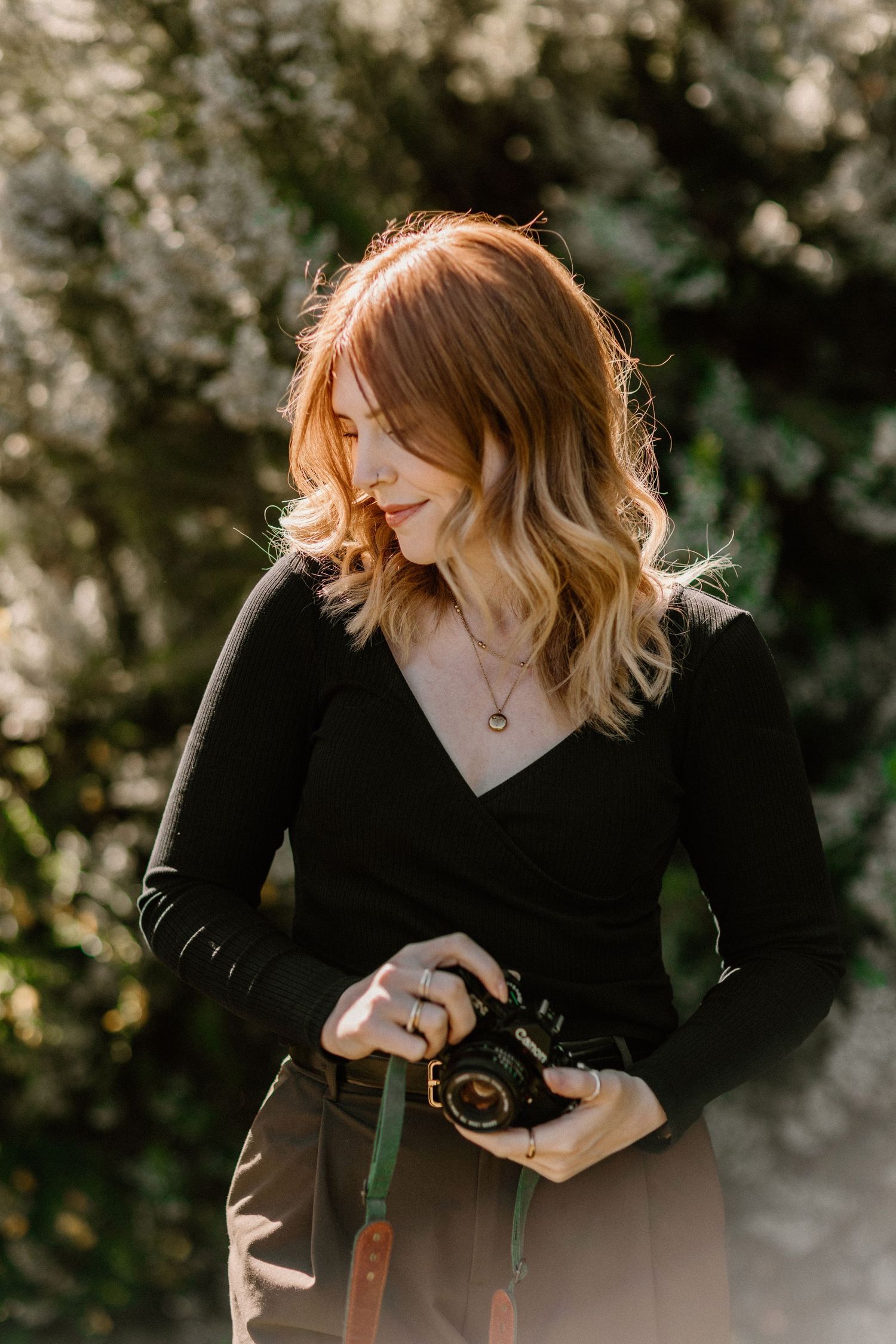 A photographer in black clothing captures images inside a stone building with vintage walls.