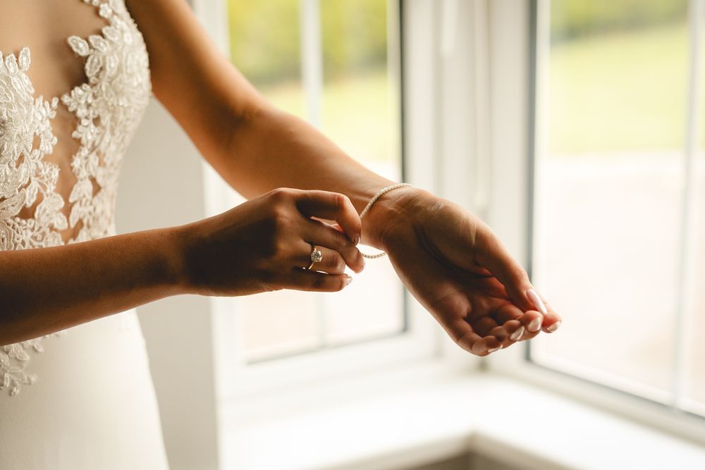 Hands delicately adjust white lace details near a sunny window.