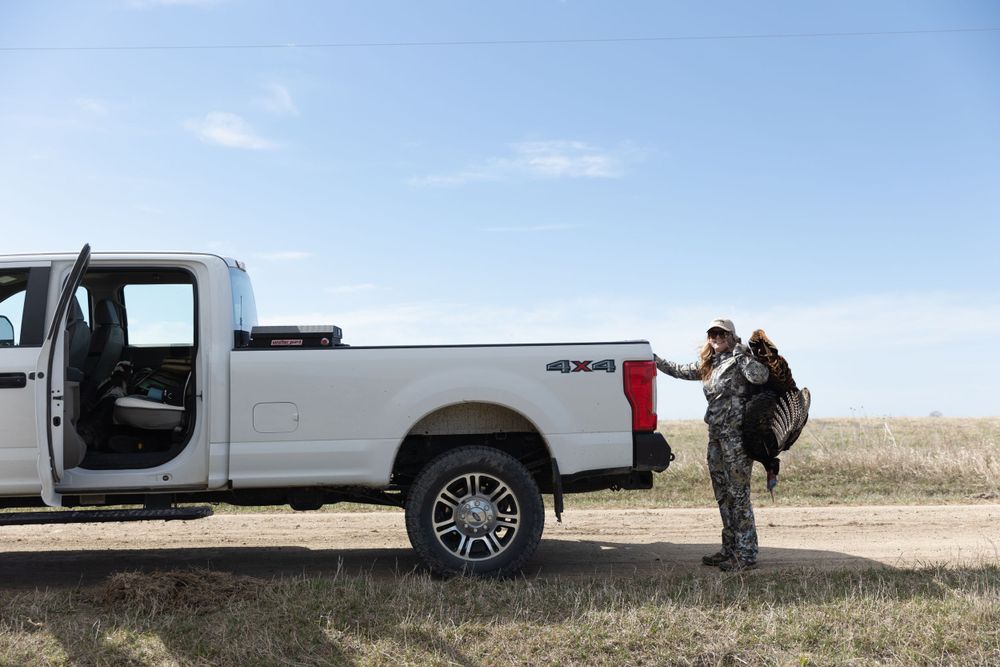 girl holding turkey over back putting down tailgate of white pickup truck