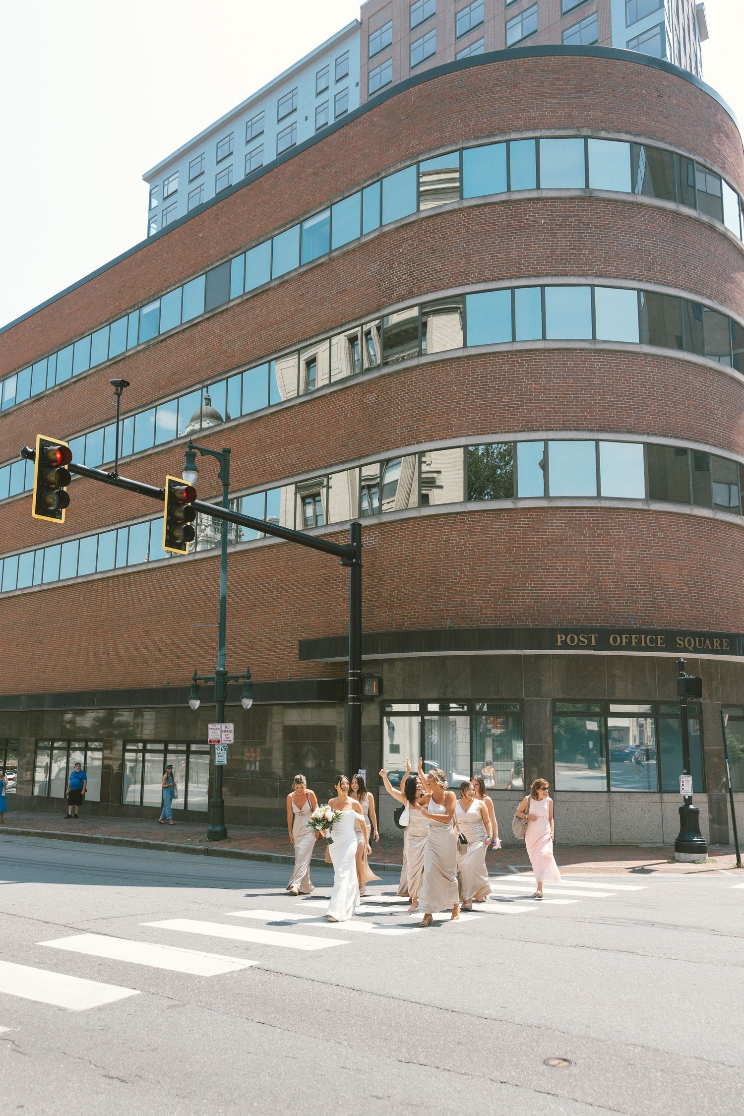Modern curved brick building with glass windows and crosswalk in urban setting.