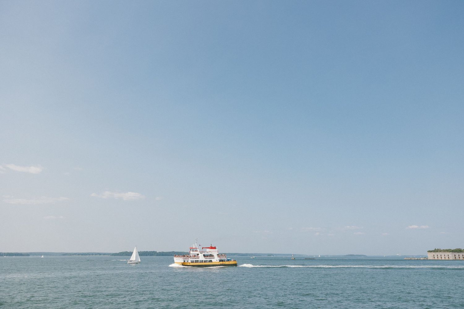 Scenic ocean view with boats visible on calm blue waters under clear sky.