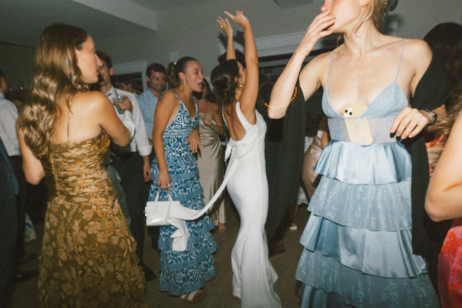 Wedding reception dance party with guests in colorful dresses dancing and having fun.