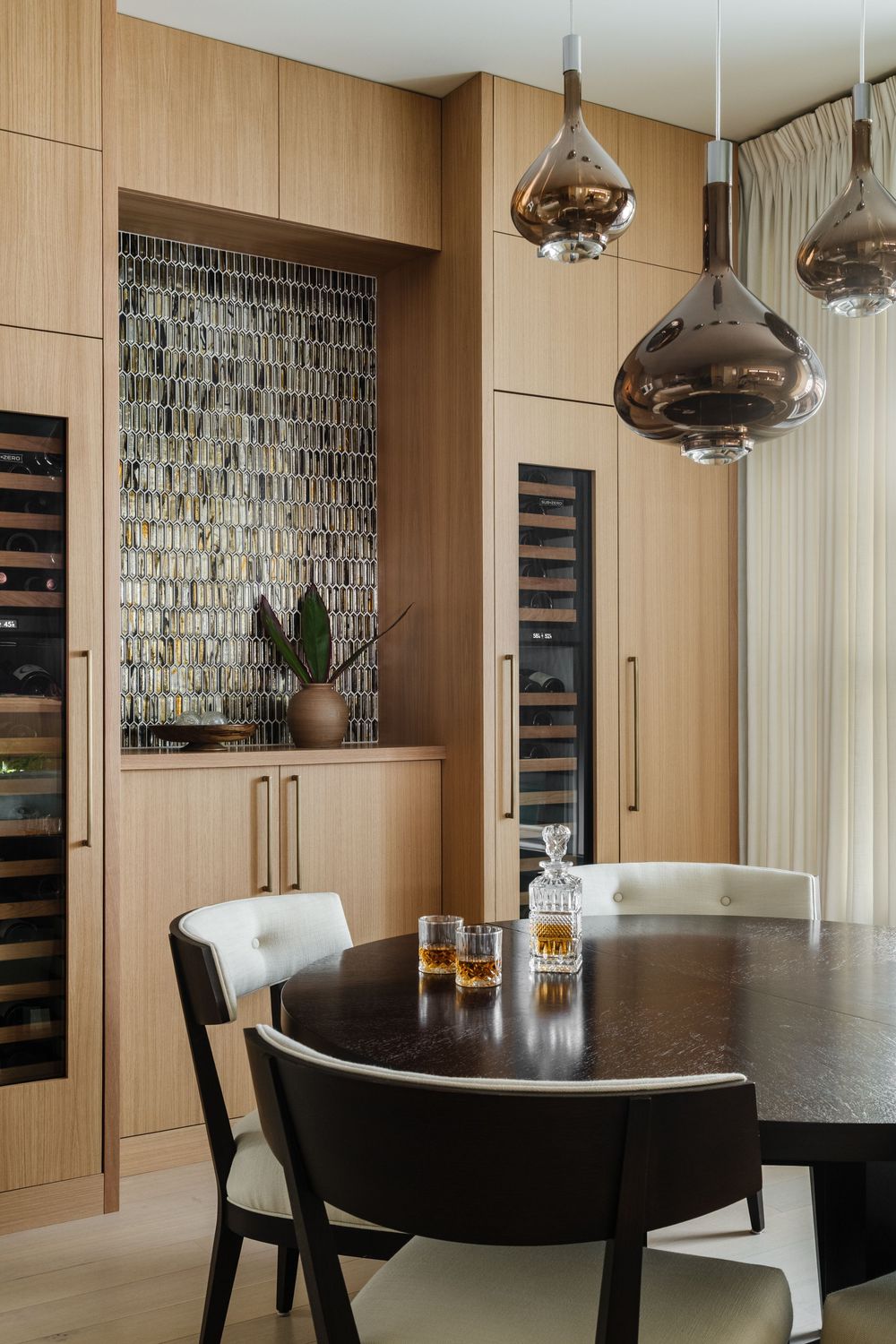 Diming room with built in wooden bar and wine fridges on either side.