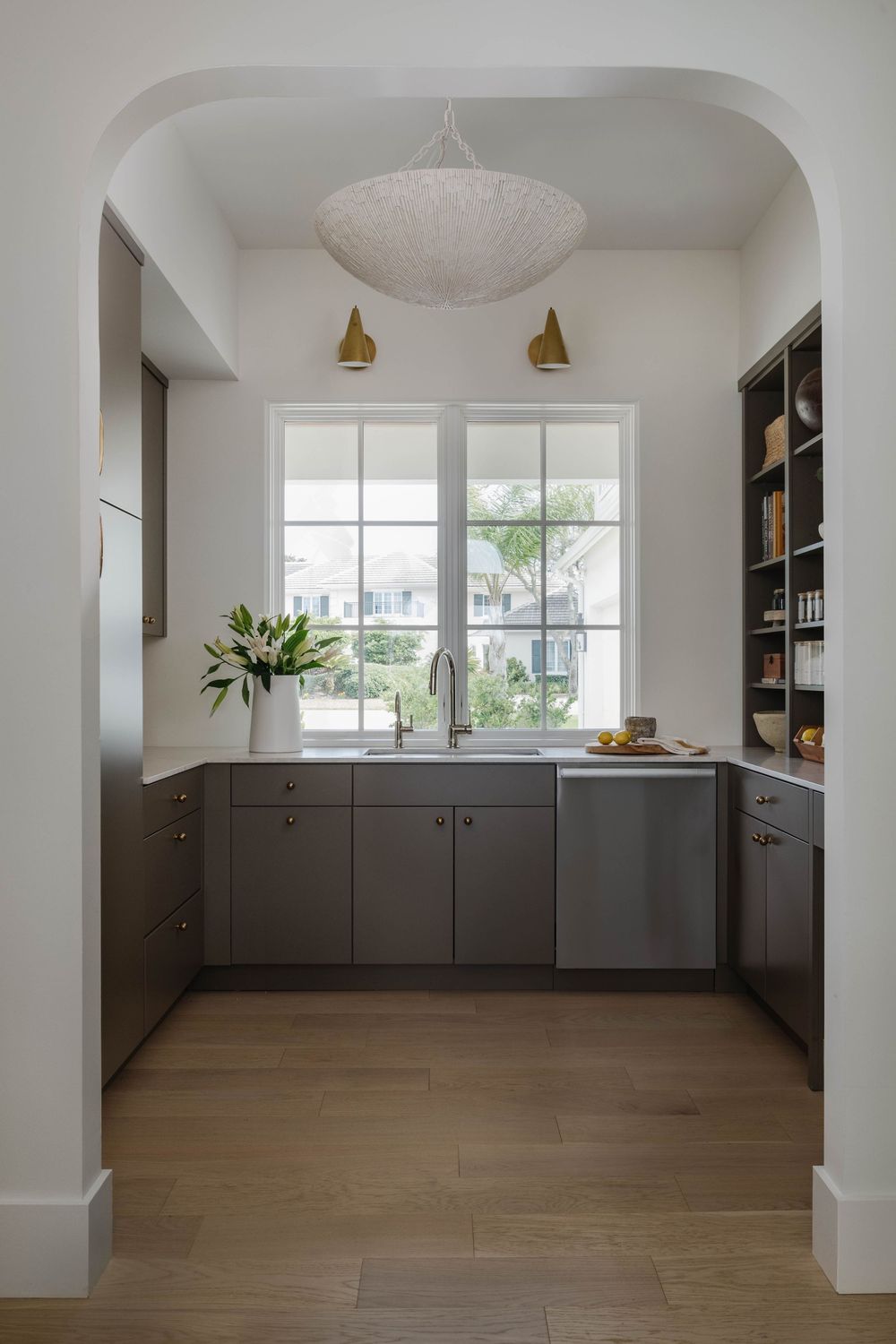 Scullery with arched entryway and dark grey cabinets