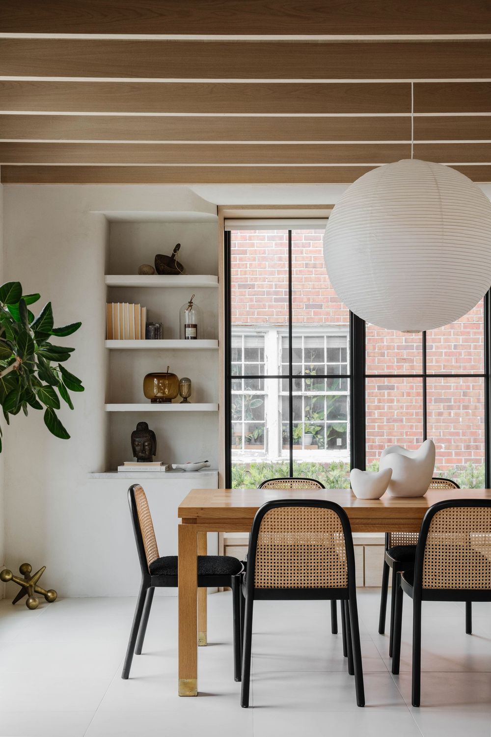 Modern dining room with plastered walls and wood ceilings and large round rice paper chandelier