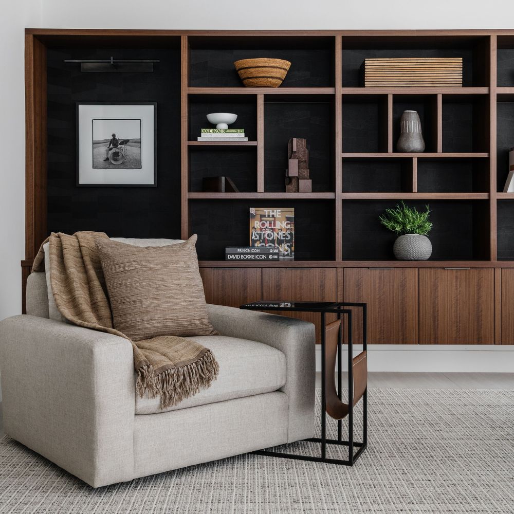 Built in dark wood shelves and cozy chair with throw
